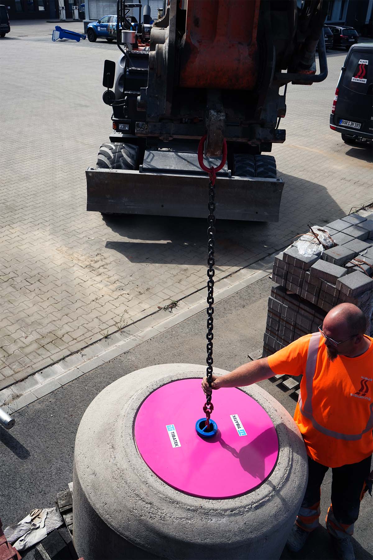 Der TIBATEK®-Asphaltdeckel wird auf einen Schacht gesetzt